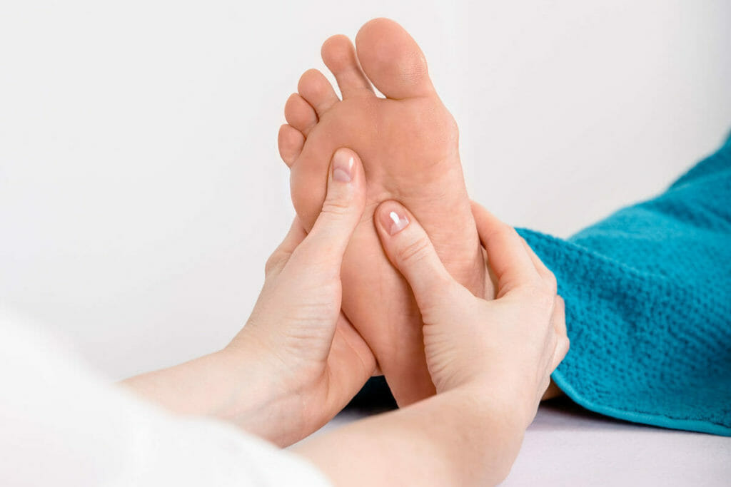 Massage der Fußreflexpunkte während der Fußreflexzonentherapie. Hier behandelt der rechte Daumen gerade die Nieren.