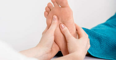 Massage der Fußreflexpunkte während der Fußreflexzonentherapie. Hier behandelt der rechte Daumen gerade die Nieren.